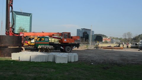 Workers and special heavy equipment in construction site near glass scyscraper houses circa May in Vilnius, Lithuania.