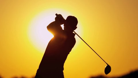 Male Caucasian golfer in sunset silhouette enjoying vacation luxury resort using driver to tee off golf course fairway slow motion shot on RED EPIC, 4K, UHD, Ultra HD resolution