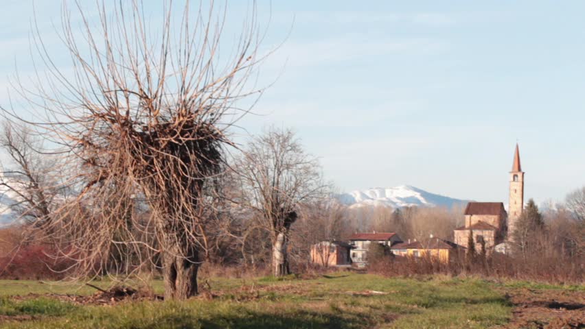 rural landscape with an ancient church (Pieve di Suno) and ski resort on Mottarone mountain in the background