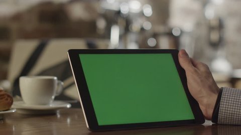 Man using Tablet in Coffee Shop. Tablet with Green Screen. Shot on RED Digital Cinema Camera in 4K, so you can easily crop and zoom, Great for presentation and mockups. Easy for tracking and keying. Arkistovideo