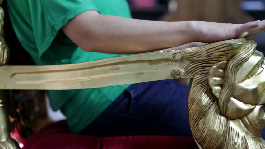 Female hand tapping the fingers on the golden chair