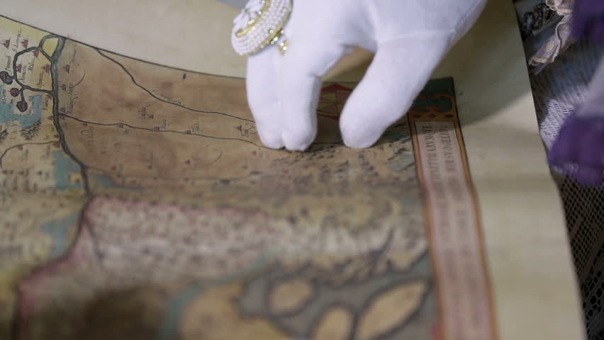 Man with white gloves is reading an old geographical map