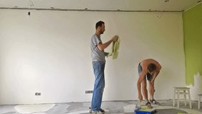 Two men painting a wall with roller. Time lapse video