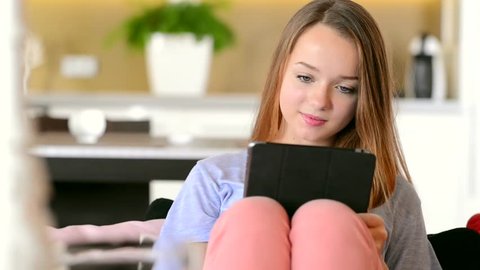 Beauty Teenage Girl with Tablet pc. Beautiful Surprised Young Woman using Tablet Computer ipad Touchscreen at home. 1920x1080 Hd Video Footage. Dolly Shot