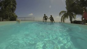 Couple jumping in infinity pool water