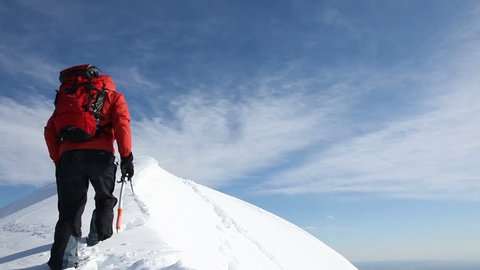Mountaineer reaches the summit of a snowy ridge and expresses his joy - low angle view - HD1080p Canon 5DMkII