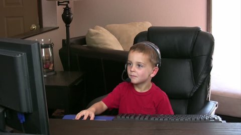 Kid playing on computer with a headset on