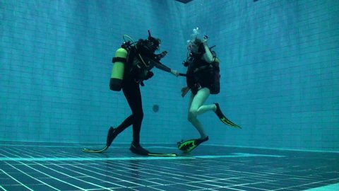 Two scuba divers going up to the surface in a deep pool