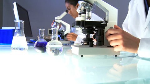 Female researchers in laboratory looking through a microscope
