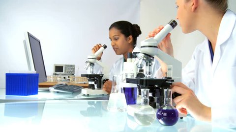 Female scientists in laboratory looking through a microscope