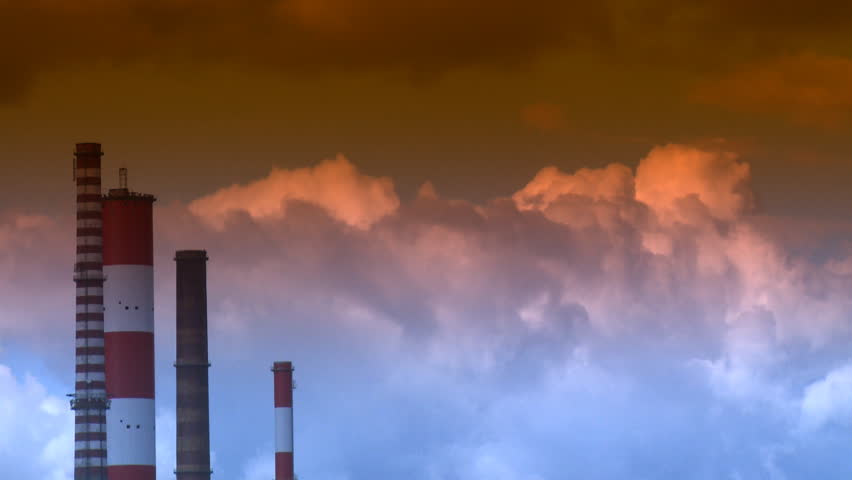 Time lapse of chimneys and white clouds over blue sky 