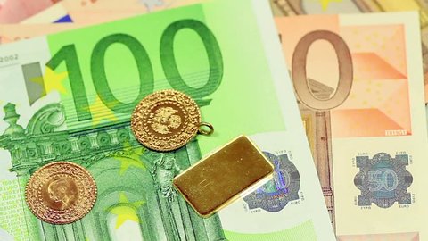 Gold coins and a goldbar falling on Euro banknotes. Closeup of European banknotes with gold coins. Perfect for any financial, commerce, treasury or banking video needs. 