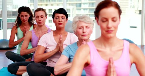 Group of peaceful women in fitness studio doing yoga at the gym