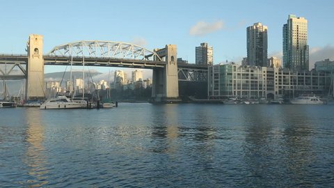 A False Creek Ferry heads towards the historic Burrard Street Bridge. The apartments of the West End neighborhood are in the background. Vancouver, British Columbia, Canada