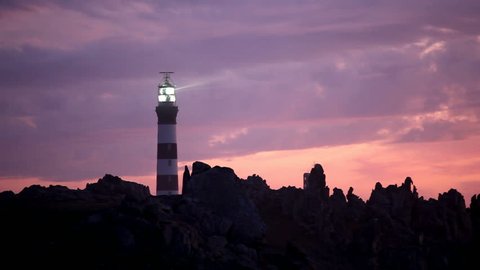 powerful lighted lighthouse at dusk, ouessant island, brittany, france