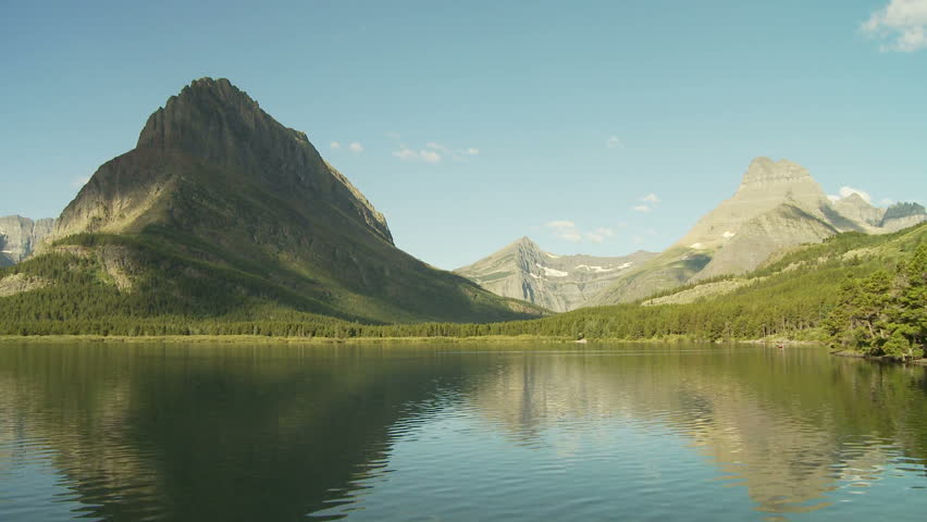 Time lapse of clouds rolling over a rugged mountains with lake