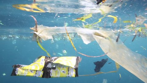 Plastic garbage and other debris floating underwater over fragile coral reef in Bunaken Island, Sulawesi