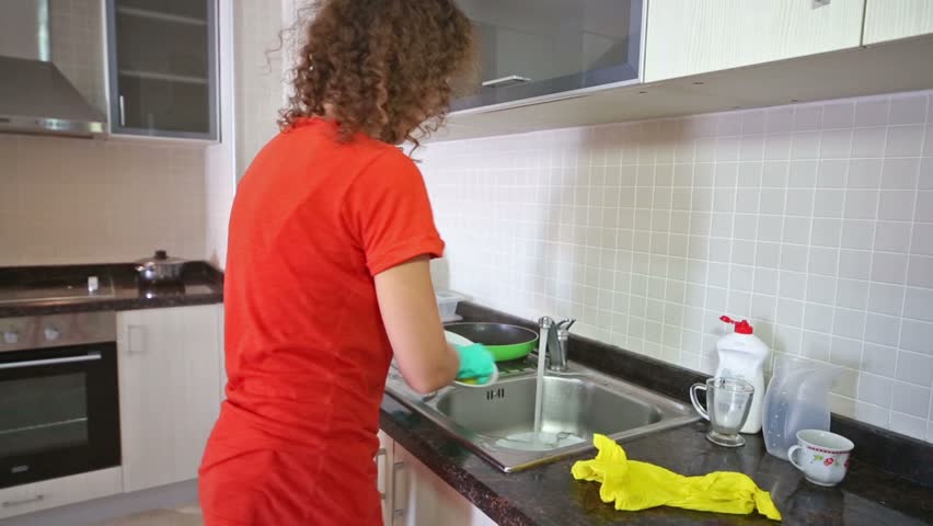 Cute housewife washing dishes with a sponge in rubber gloves | Shutterstock HD Video #5403095