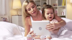 Young mother showing how to use a touchpad to her little daughter