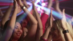 Excited nightclub audience clapping and jumping and dancing with energy
