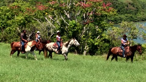 Kauai, Hawaii - May 2012: Vacationers take a horseback tour along the coastline of the northern shores of Hanalei Bay.