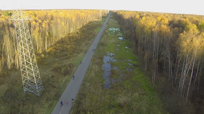 People ride on bicycles by road in park on Elk Island at sunny autumn day