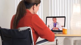 Disabled mature patient talking to senior doctor on computer