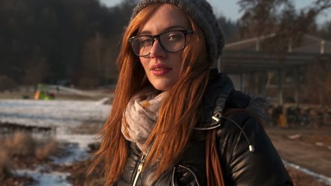 Pretty Young Girl Wearing Glasses Walks In The Park. Looks At Camera And Smiles.