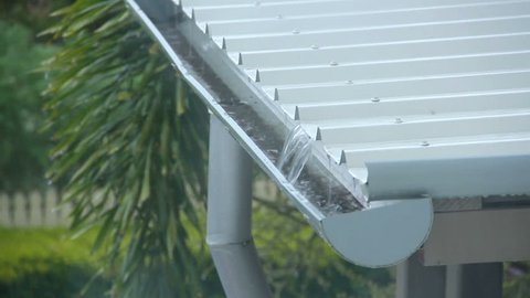 Rain pouring onto a corrugated aluminium roof running down into the gutters.