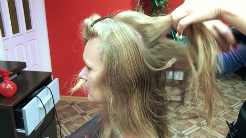  hairdresser comb separate strands customer long blonde hair on September 29, 2013 in Sirvintos, Lithuania.