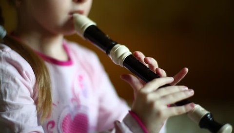 little girl playing flute (English flute, recorder, 	blockflute), beautiful macro shot with soft focus