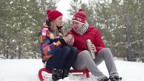 Young couple sitting outdoors and drinking hot tea on a winter day
