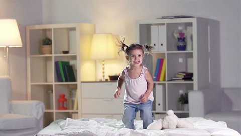 Slow-motion of a carefree girl jumping on the bed: stockvideo