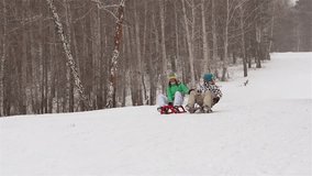 Slow-motion of a happy couple sledding on a snowy winter day