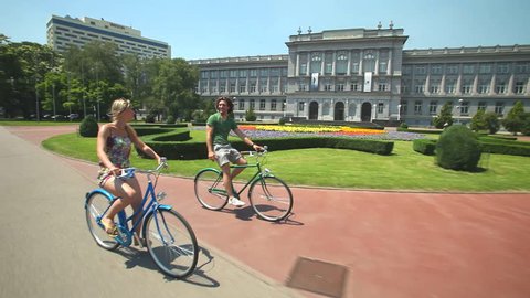 Young couple enjoying cycling through city in summer