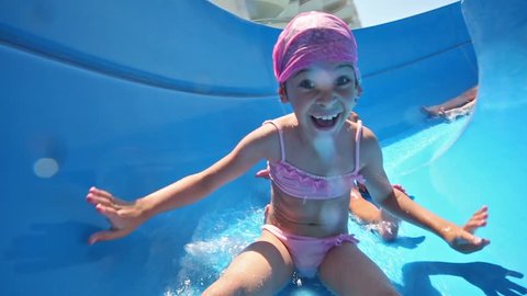 two girls and boy rolls on blue waterslide and smiles