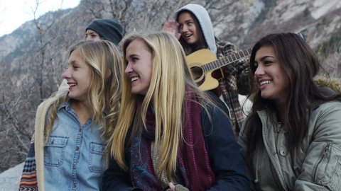 Five Bundled Up Teen Girls, One Playing Guitar, Four Waving At Friends Off-screen