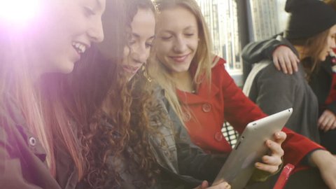 Lens Flare Shot Of Six Teen Girls Waiting At A Station With A Phone And A Tablet