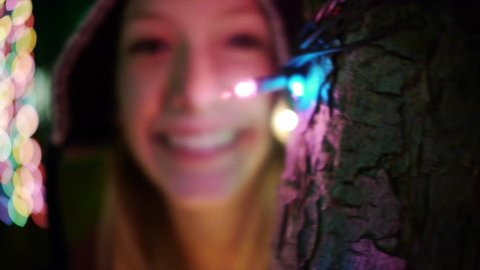 Adorable Teen Girl Peers From Behind Tree Lit For The Holidays - Slo Mo Close Up วิดีโอสต็อก