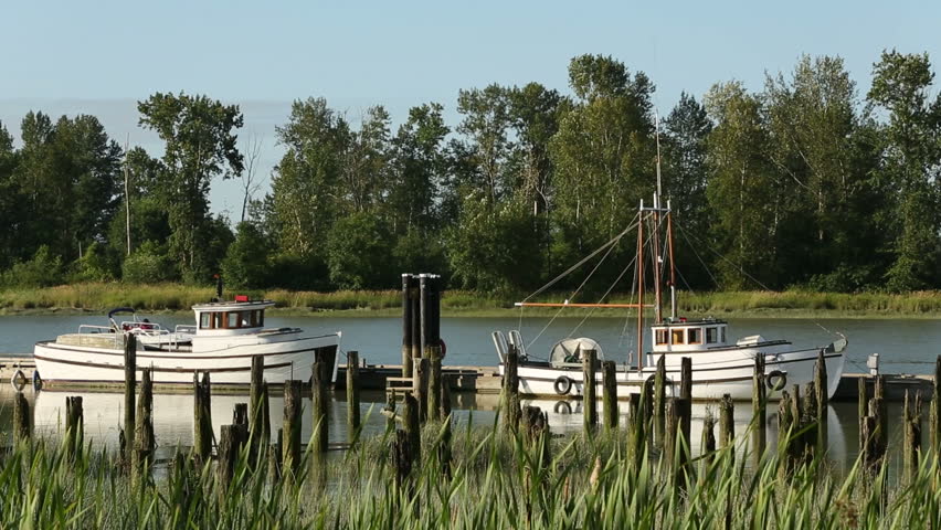 The docks of the Brittania Heritage Shipyard in Steveston BC on the banks of the Fraser River. A family in a runabout passes by in the background. Near Vancouver, British Columbia, Canada.