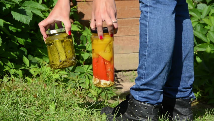 girl goes to the basement overgrown with green creepers carrying jars with pickled cucumbers peppers