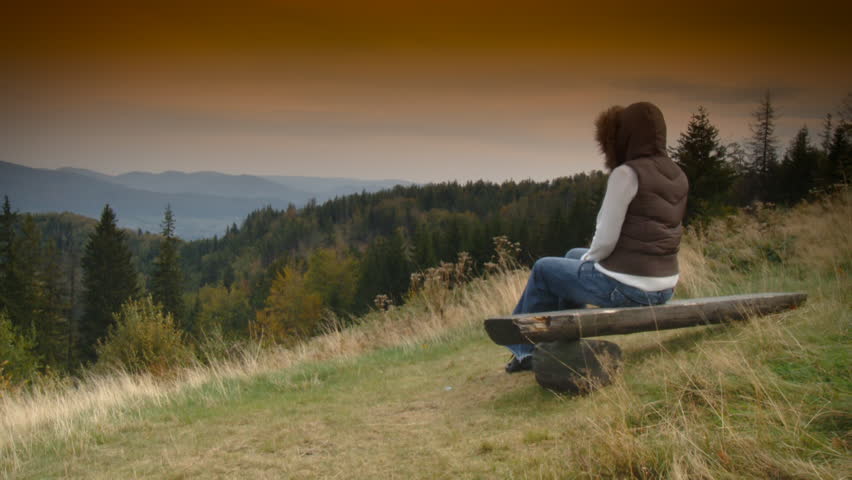 Woman is relaxing on bench, mountain landscape 