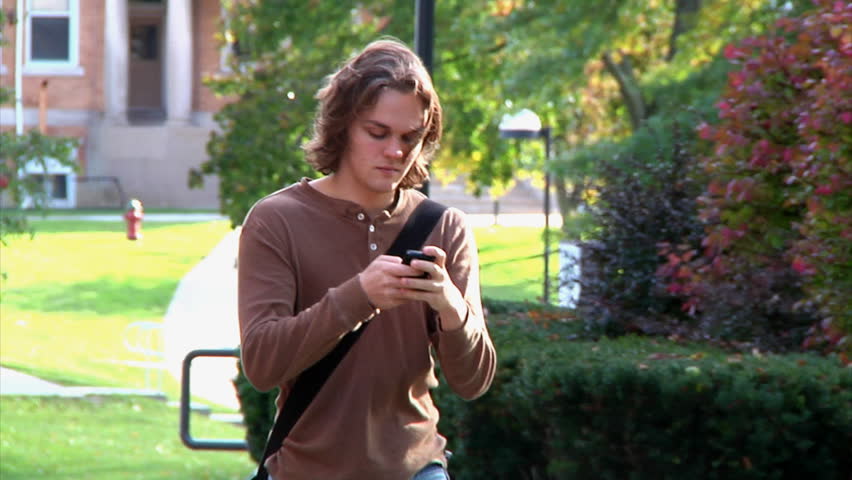 Student texting while walking on campus.