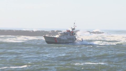 United States Coast Guard speeding through harbor waters in the Pacific Northwest coastline on sunny day.