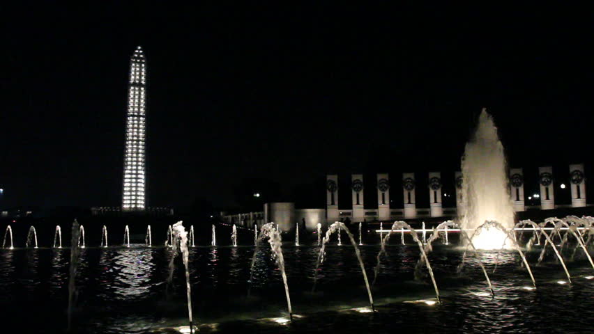 Fountains of the World War II memorial and the Washington Monument covered in scaffolding in Washington, DC at night