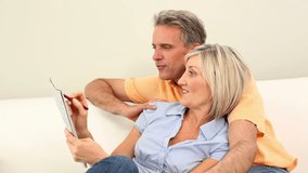 Couple laughing together on the couch doing the crossword puzzle at home in the living room - Powered by Shutterstock - Get 15% off with code: PIKWIZARD15