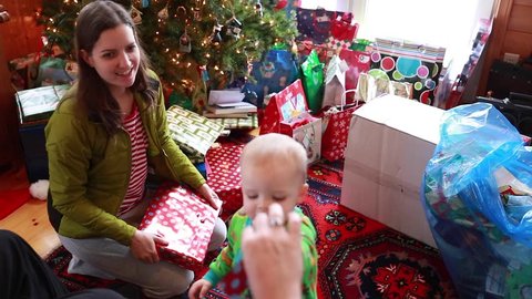 A family opening their christmas presents on christmas morning with a toddler