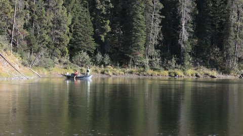 Fishing on Snake River inside Grand Teton National Park, Wyoming. Oar boat fishing in an outdoor adventure. Fun in the wilderness area. Fly fishing and recreation with a guide. 