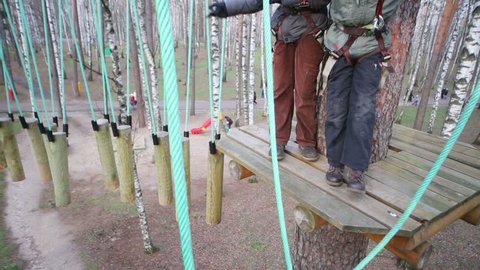 Legs of children standing on wood of rope course at autumn day