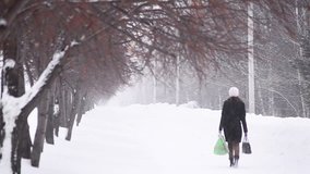 Young woman comes back after shopping through heavy snowfall in winter
